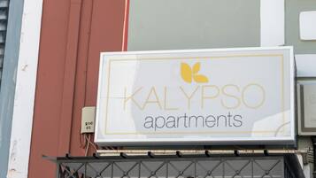 A sign for KALYPSO apartments with a yellow logo and text.