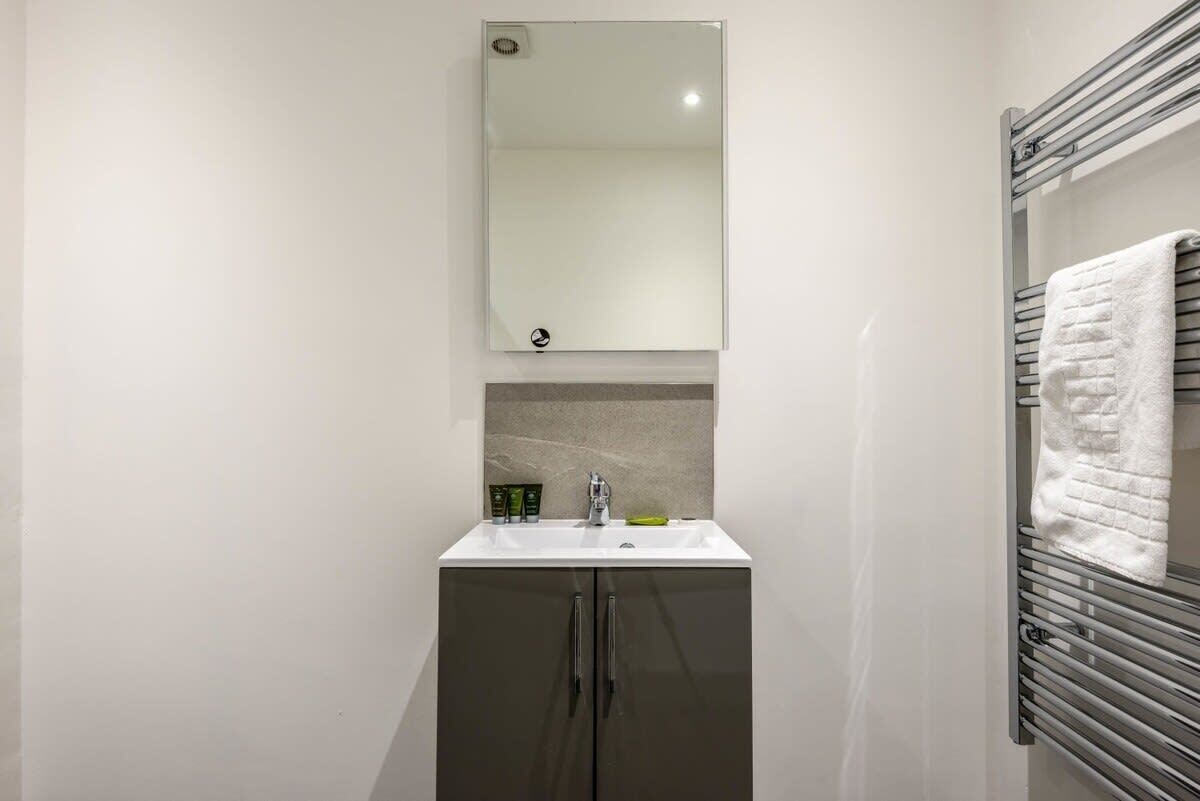 Un baño pequeño con un lavabo blanco, un espejo y un perchero para toallas.