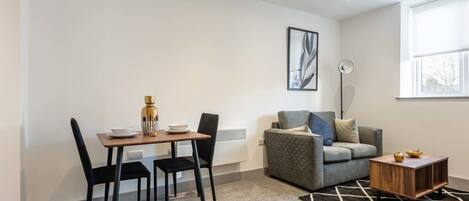 A modern living room with a dining table, chairs, a sofa, and a coffee table.