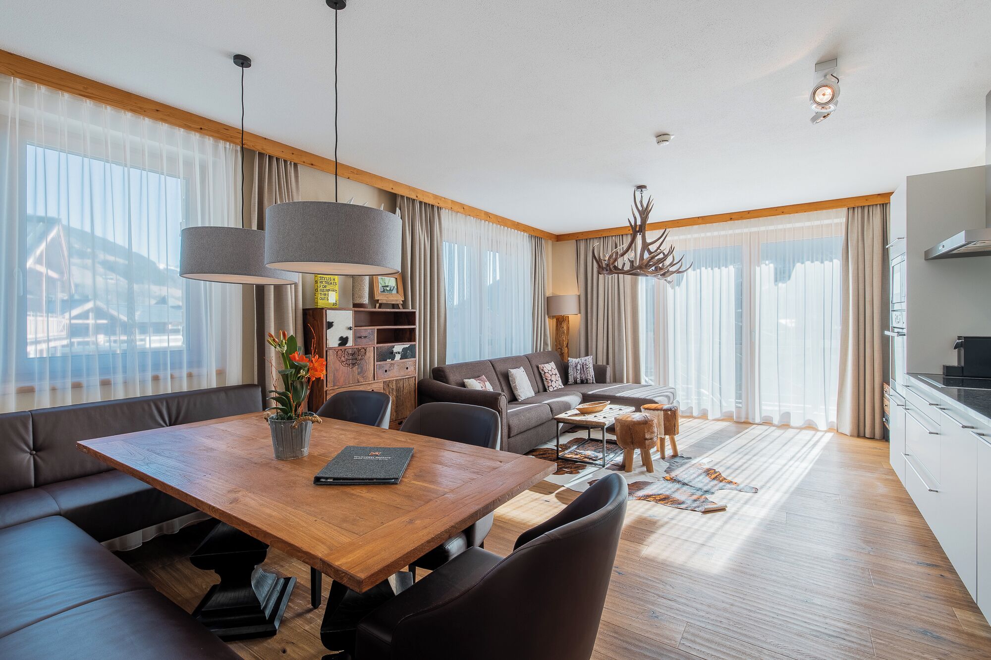 Een moderne woonkamer met een houten eettafel, een bank en een keukenhoek.