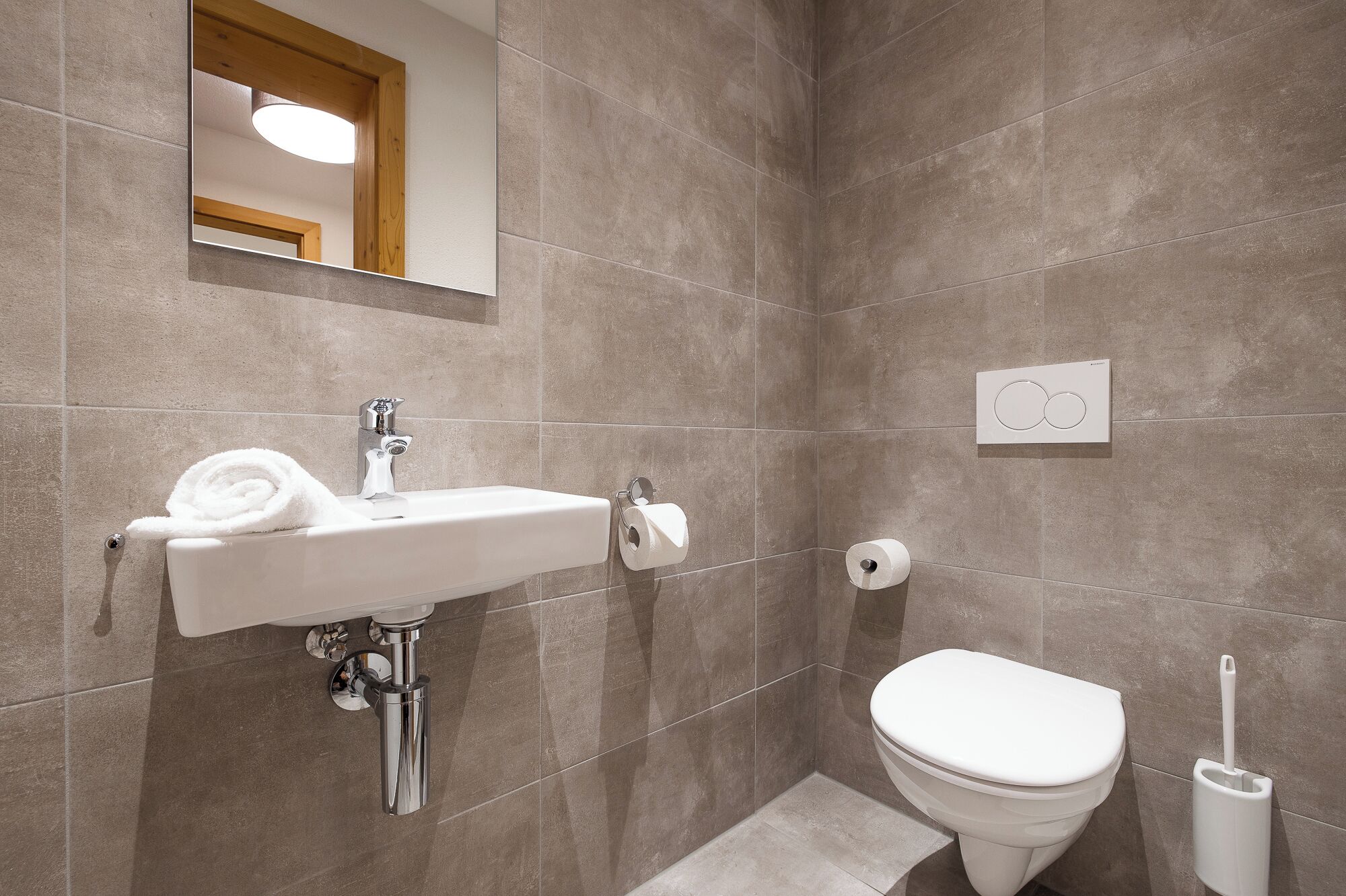Une salle de bain avec un lavabo blanc, des toilettes et un miroir au-dessus du lavabo.
