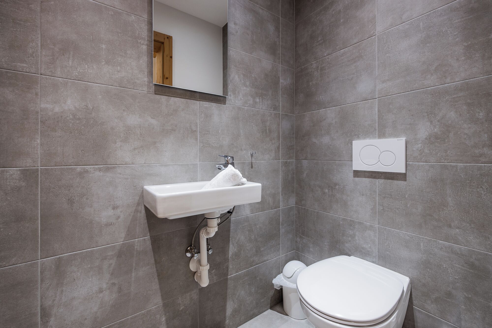 A bathroom with a white sink, toilet, and a mirror.