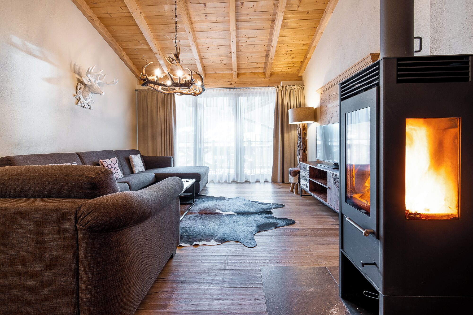 A cozy living room with a fireplace, wooden ceiling, and a leather sofa.