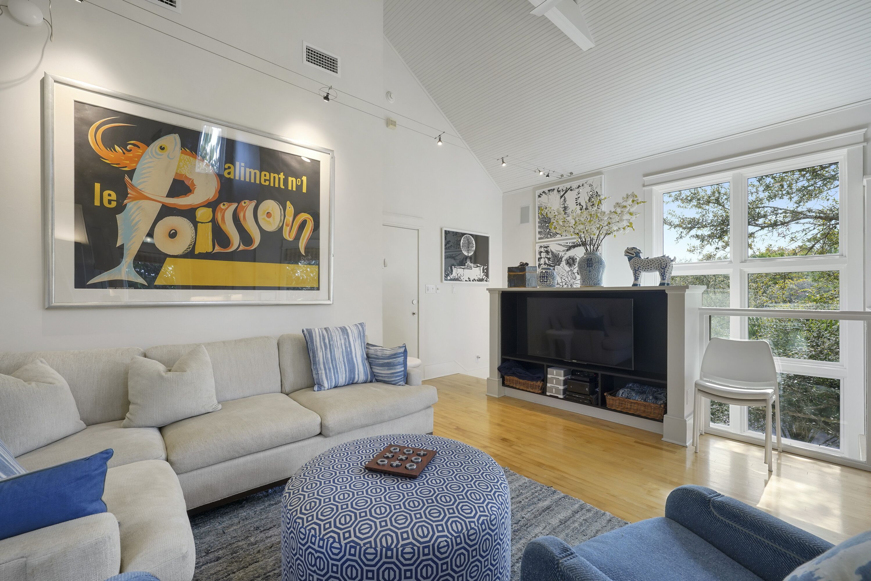 A modern living room with a sofa, ottoman, and a large framed artwork.