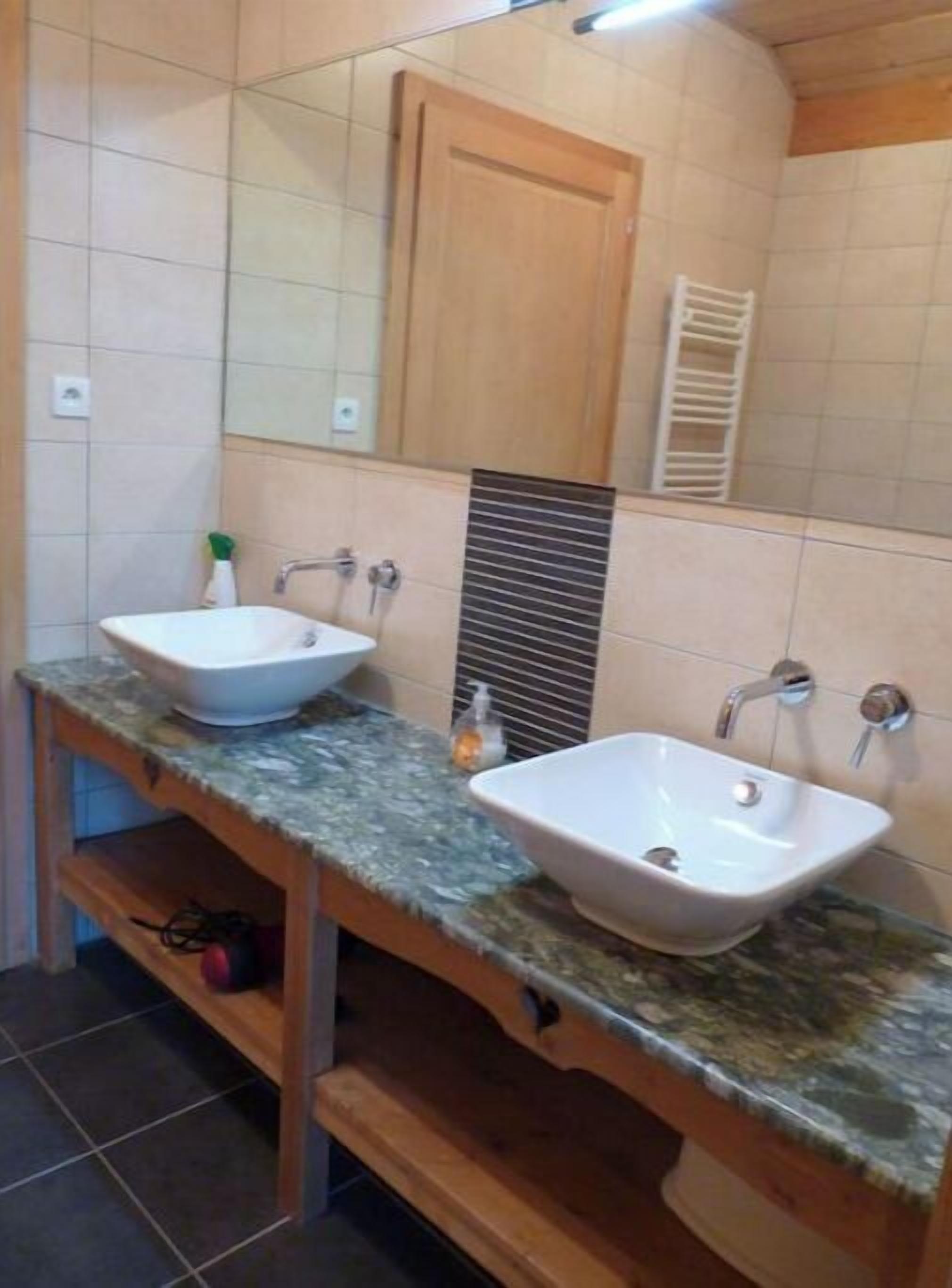 Ein Badezimmer mit zwei Waschbecken, einem Spiegel und einem Holzschrank.