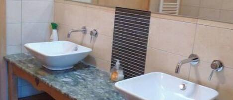 Ein Badezimmer mit zwei Waschbecken, einem Spiegel und einem Holzschrank.