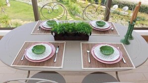 A dining table set for four with placemats, plates, cutlery, and a centerpiece of greenery. - Apartment Amelo, fantastic clean apartment near marina (Albufeira)