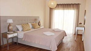A neatly arranged bedroom with a large bed, two bedside tables with lamps, a bedside mirror, and a hanging light fixture. - Apartment Amelo, fantastic clean apartment near marina (Albufeira)