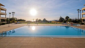 Une piscine offrant une vue dégagée sur les environs, notamment sur un immeuble à plusieurs étages et des palmiers.
