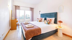 Une chambre d’hôtel moderne, dotée d’un grand lit, d’un bureau et offrant une vue sur l’extérieur.