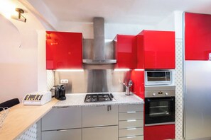 A compact kitchen with a gas stove, a built-in microwave, and a stainless steel range hood.