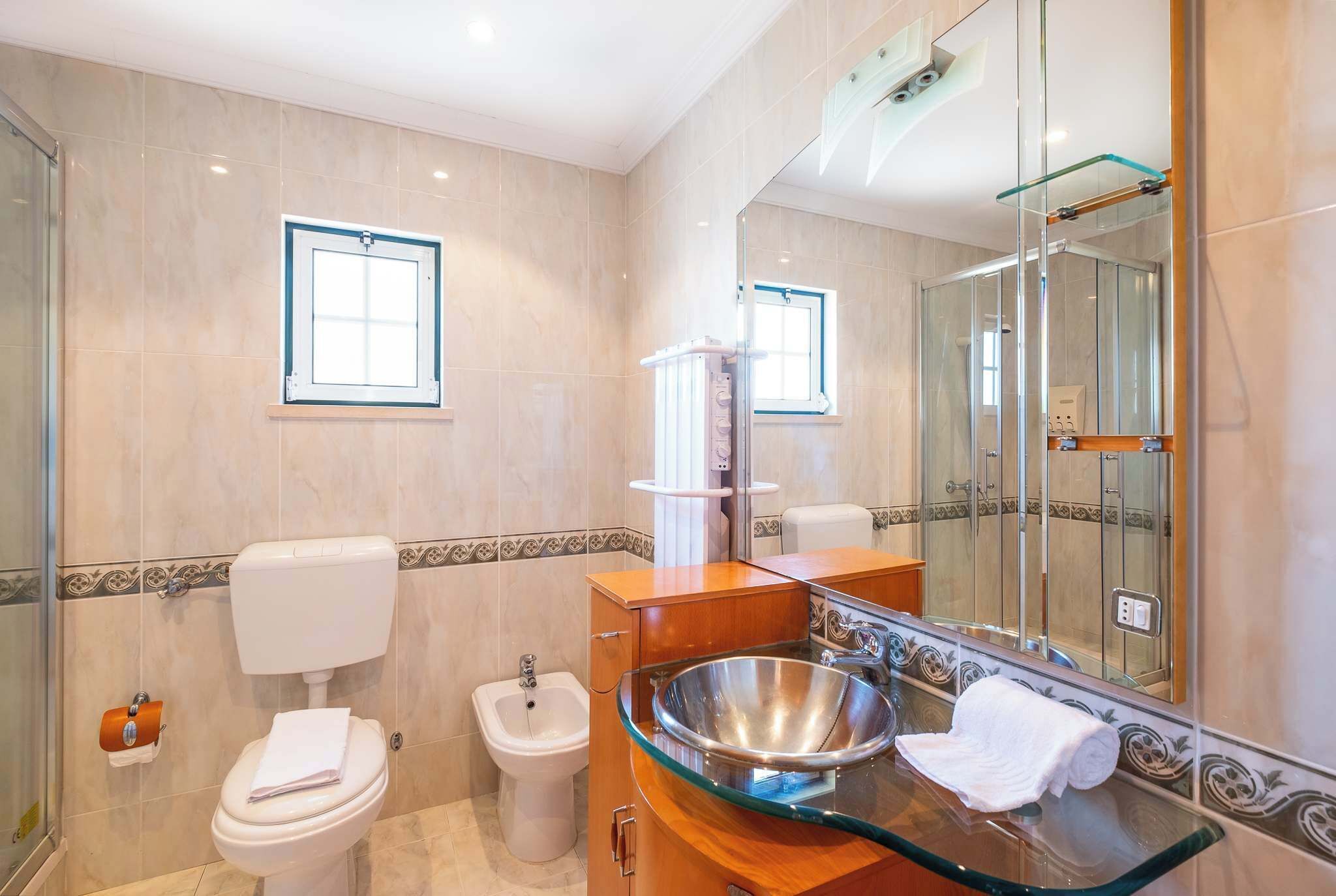 Et badeværelse med vask, toilet, bidet og et stort spejl.