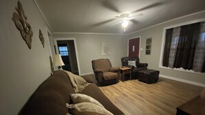 A living room with a brown sofa, two armchairs, a wooden coffee table, and a ceiling fan. - Cozy Gilbert House (Gilbert)