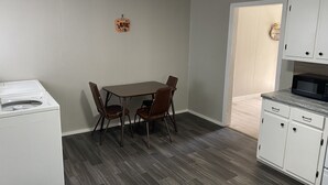 A compact kitchen with a microwave, cabinets, and a dining table with chairs. - Cozy Gilbert House (Gilbert)