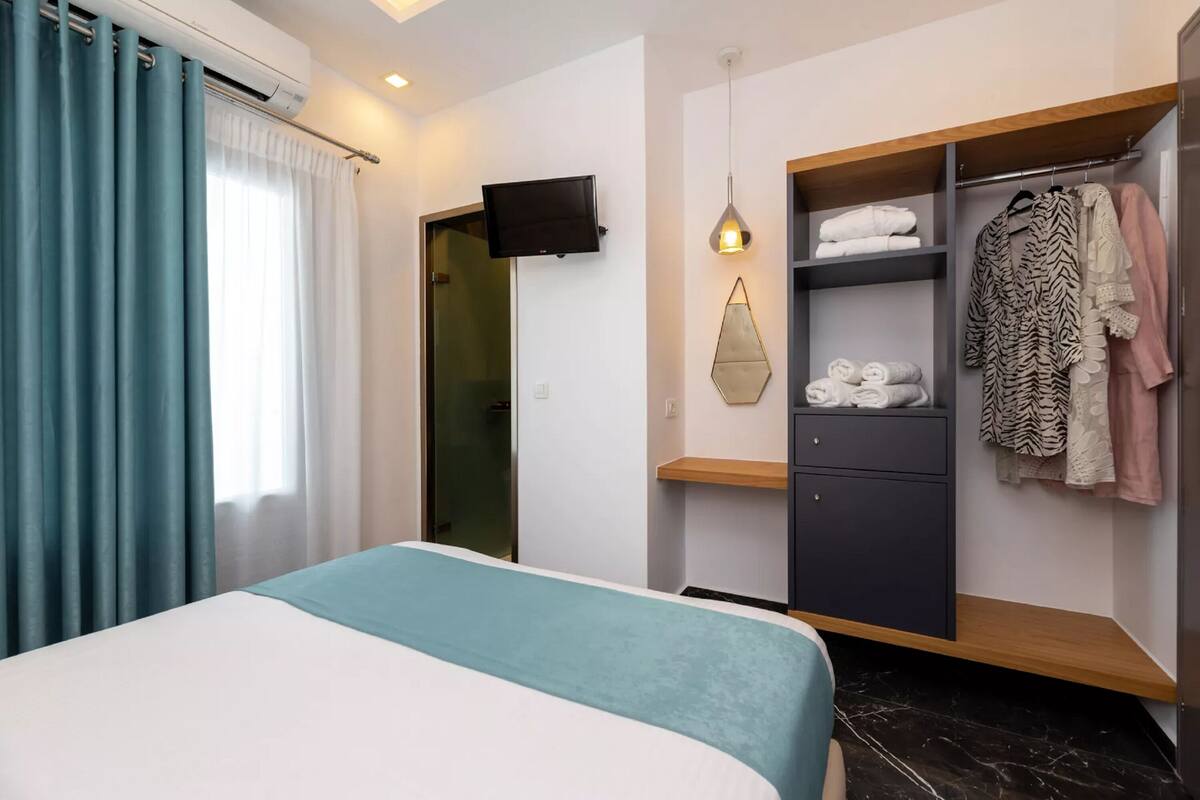 A modern hotel room with a bed, a wardrobe, and a television.