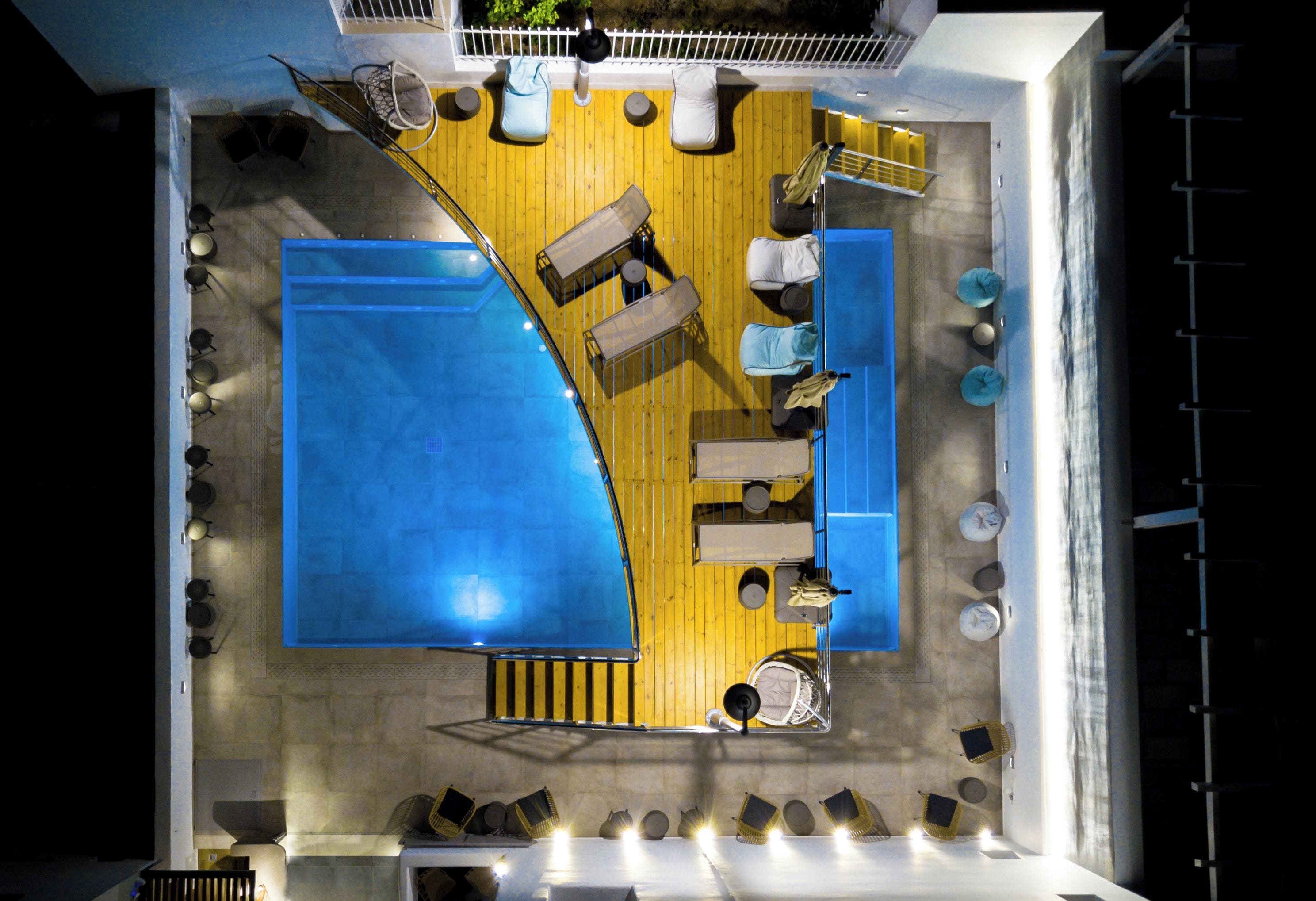 Vue d’ensemble d’une terrasse avec une piscine, des espaces aménagés pour s’asseoir et un coin bar.