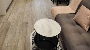 Un espacio habitable compacto con sofá, una mesita redonda, una zona de cocina y una mesa de comedor con sillas.