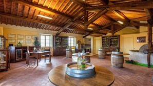 Un interior rústico con mesas de barril de madera, una zona de bar y una estantería para vinos.