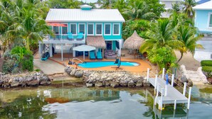 A house with a pool, a deck, and a thatched roof. - Beachfront 3B/3B Fishing Oasis (Ramrod Key)