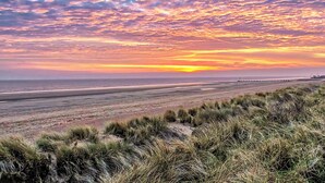 Une plage avec des dunes et un coucher de soleil.