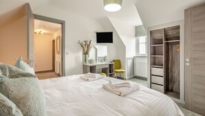 Une chambre à coucher comprenant un lit, un bureau, une chaise, une armoire et un téléviseur.