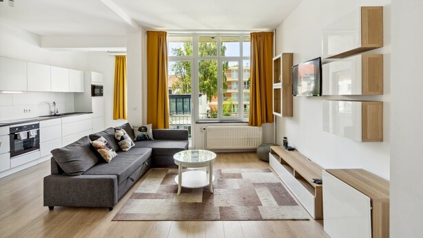 Un appartement moderne comprenant une cuisine, un espace de vie et une grande fenêtre avec des rideaux.