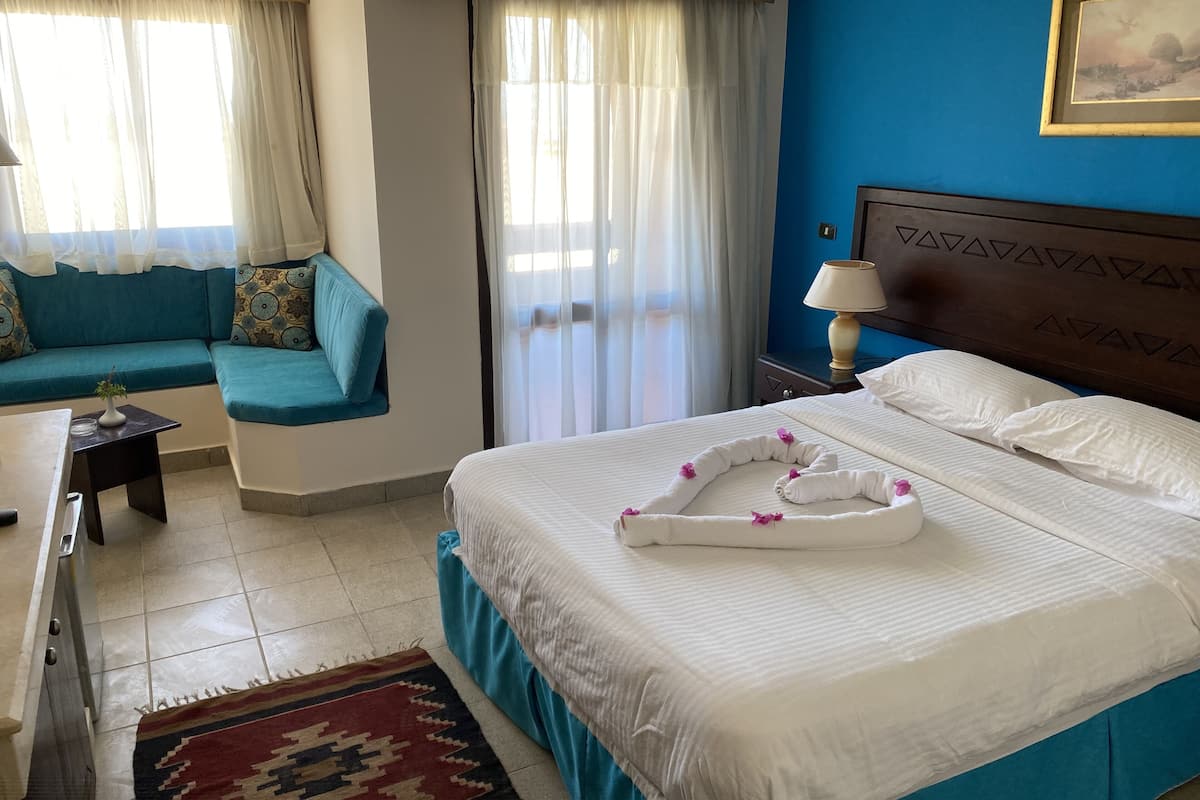 A hotel room with a bed, a sofa, a small table, and a nightstand.