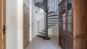 Un escalier en colimaçon avec une rampe en métal, des portes en bois et une grande armoire en bois.