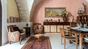Une pièce chaleureuse avec une table à manger en bois, des chaises, un tapis à motifs, un canapé et un meuble contenant des objets décoratifs.