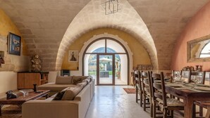 Un vaste espace de vie doté d’un haut plafond en arc de cercle, d’une table à manger pouvant accueillir six personnes et d’une grande fenêtre offrant une vue sur l’extérieur.