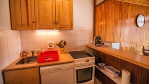 Eine Küche mit Holzausstattung, einem Geschirrspüler, einem Backofen und einer Arbeitsplatte mit einem roten Tablett und Küchenutensilien.