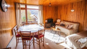 Ein Holzinterieur mit Esstisch, Stühlen, einer Couch und einem Fernseher.