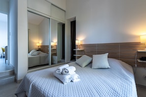Une chambre d’hôtel moderne avec un grand lit, un miroir et une tête de lit en bois.