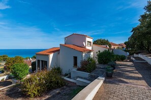 A coastal residential area with houses featuring red-tiled roofs and white walls.