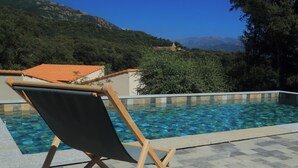 Ein Poolbereich mit Liege und Bergblick.