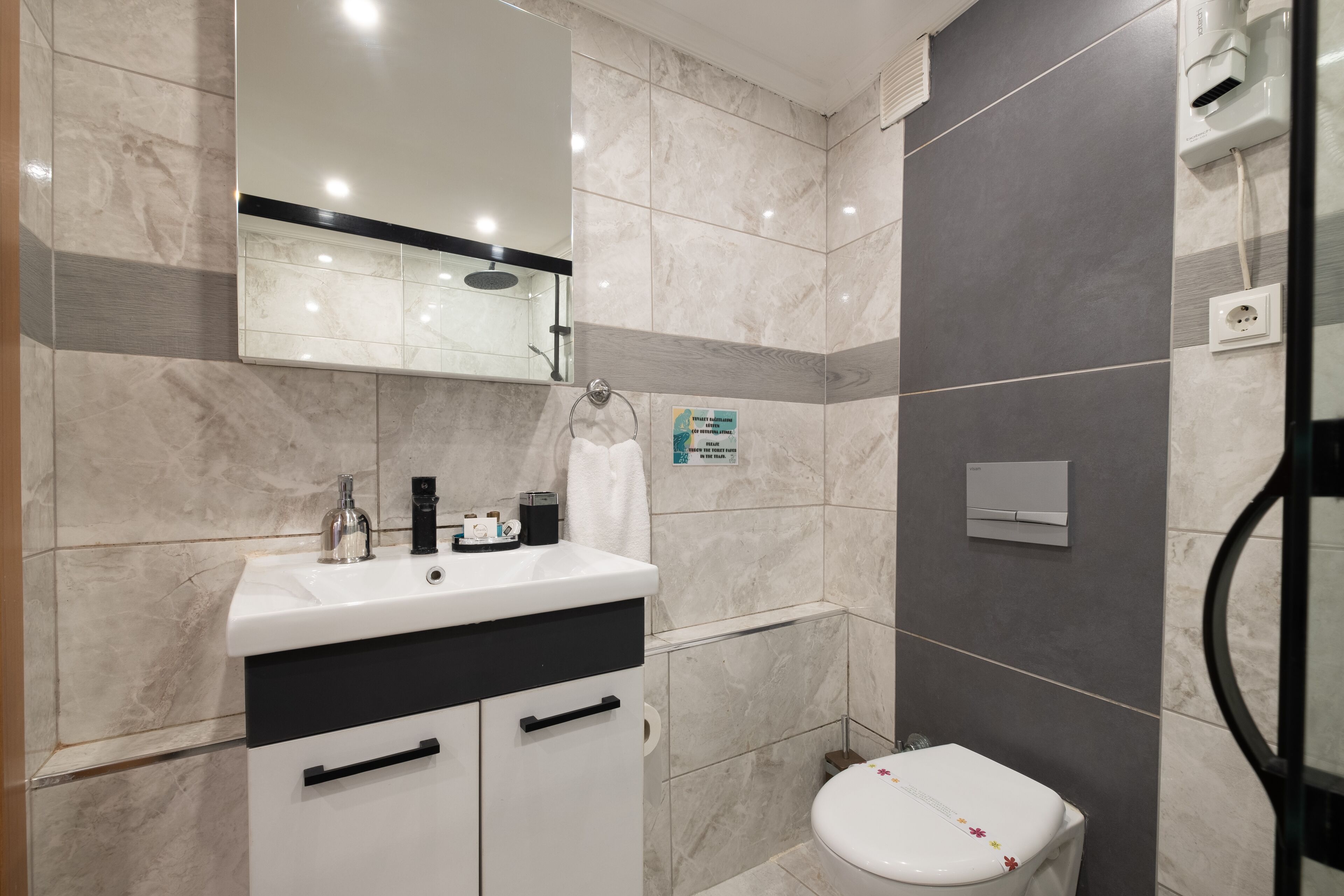 Un baño moderno con un lavamanos blanco, un mueble negro y un inodoro.
