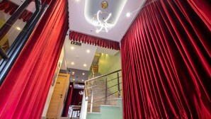 A staircase with red curtains on both sides, a modern light fixture, and a green wall in the background.