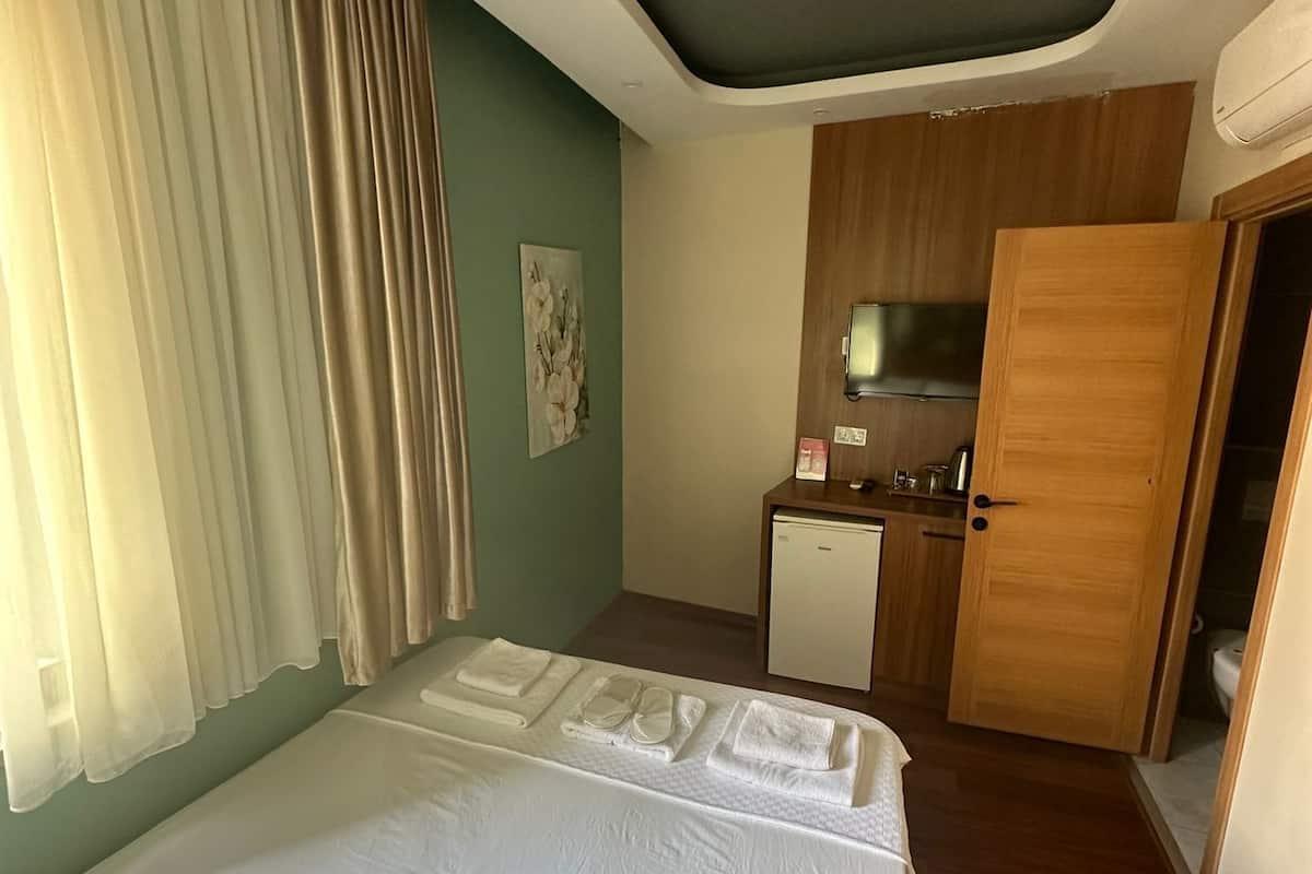 A hotel room with a bed, a kitchenette, and a bathroom.