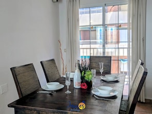 A dining table set with white plates, bowls, and glasses, with a vase of flowers and a bottle of champagne.