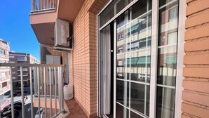 Un balcón con puerta corredera de vidrio, un equipo de aire acondicionado blanco y un dispensador de agua blanco de gran tamaño.