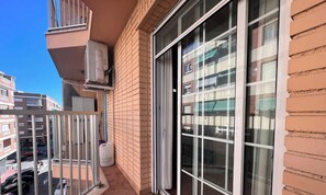 A balcony with a sliding glass door, a white air conditioning unit, and a large white water dispenser.