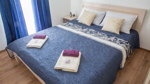 A neatly made bed with a patterned bedspread, two pillows, and two folded towels.
