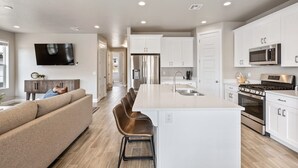 A modern kitchen with white cabinetry, stainless steel appliances, and a central island. - Grand Getaway: Sleeps 20, reunion or corporate (Washington)