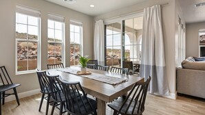 A dining area with a large table, chairs, and a view of a rocky landscape through large windows. - Grand Getaway: Sleeps 20, reunion or corporate (Washington)