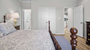 Un dormitorio con una cama, una mesita de noche, una lámpara y un aparador.