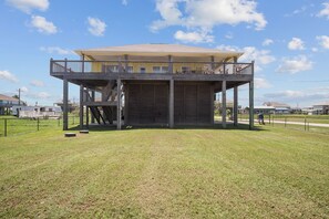 A two-story building with a balcony on the upper level, a staircase leading to the upper floor, and a fenced area in front.