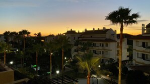 A residential area with multi-story buildings, palm trees, and a sunset in the background. - Beautiful apartment (Mijas)