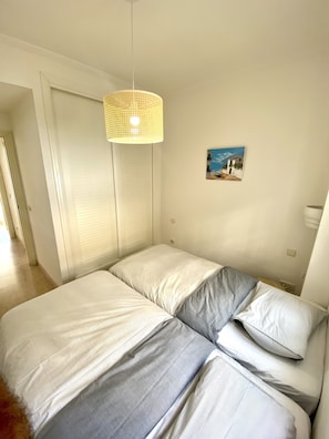 A bedroom with a bed, a hanging light fixture, and a painting on the wall.