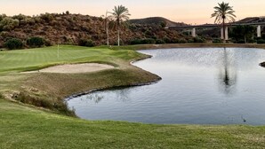 A golf course with a pond, palm trees, and a bridge in the background. - Beautiful apartment (Mijas)