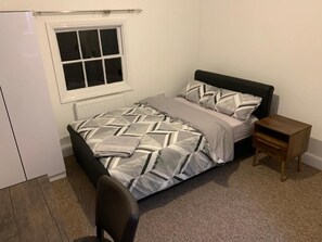 A bedroom with a bed, a nightstand, a chair, and a window. - Castle Hill Resident (Cambridge)